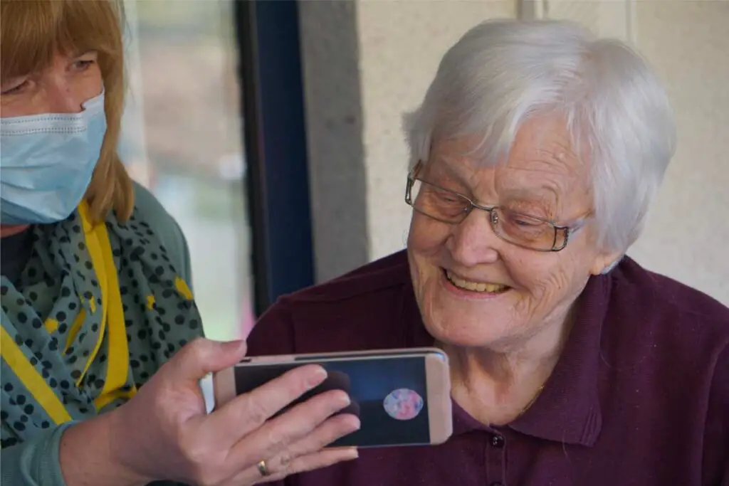 an older woman learning some winter safety tips for seniors with a masked caregiver, including the warning signs of hypothermia