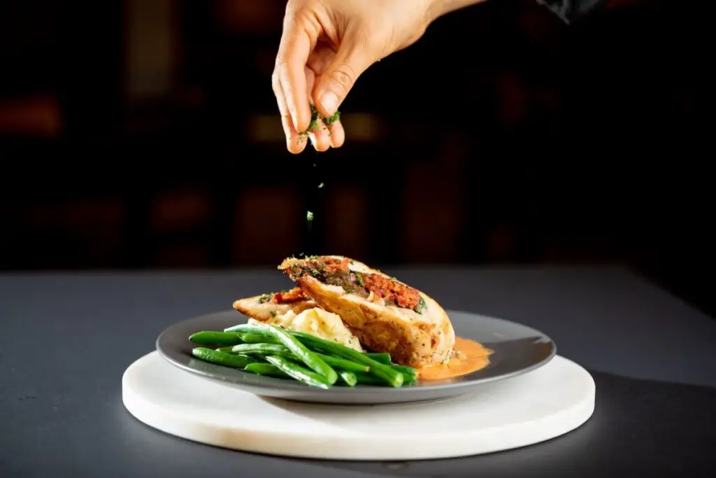 a plate of food being sprinkled with seasoning