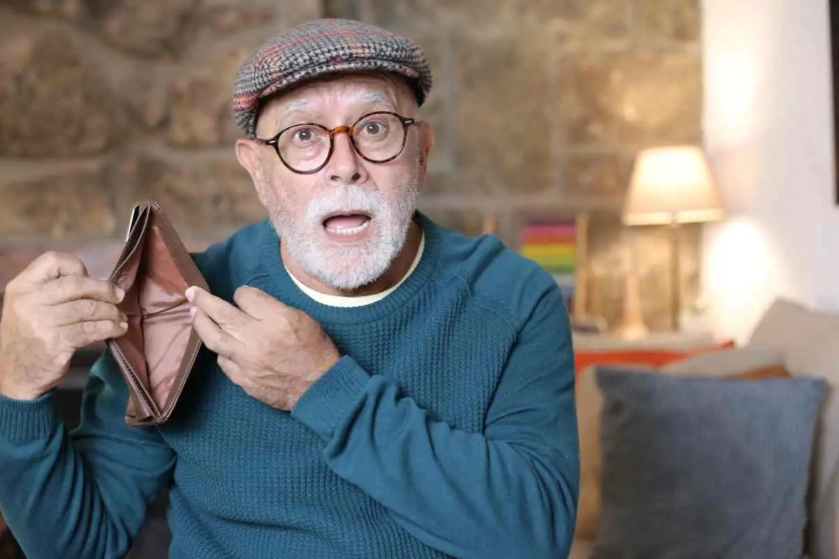 elderly man holding an empty wallet open wide with a look of surprise