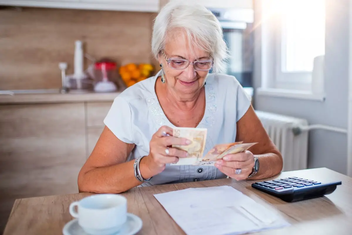 happy senior woman at desk counting money