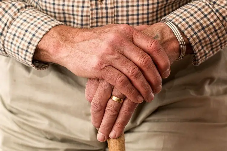 An older man's hands with cane