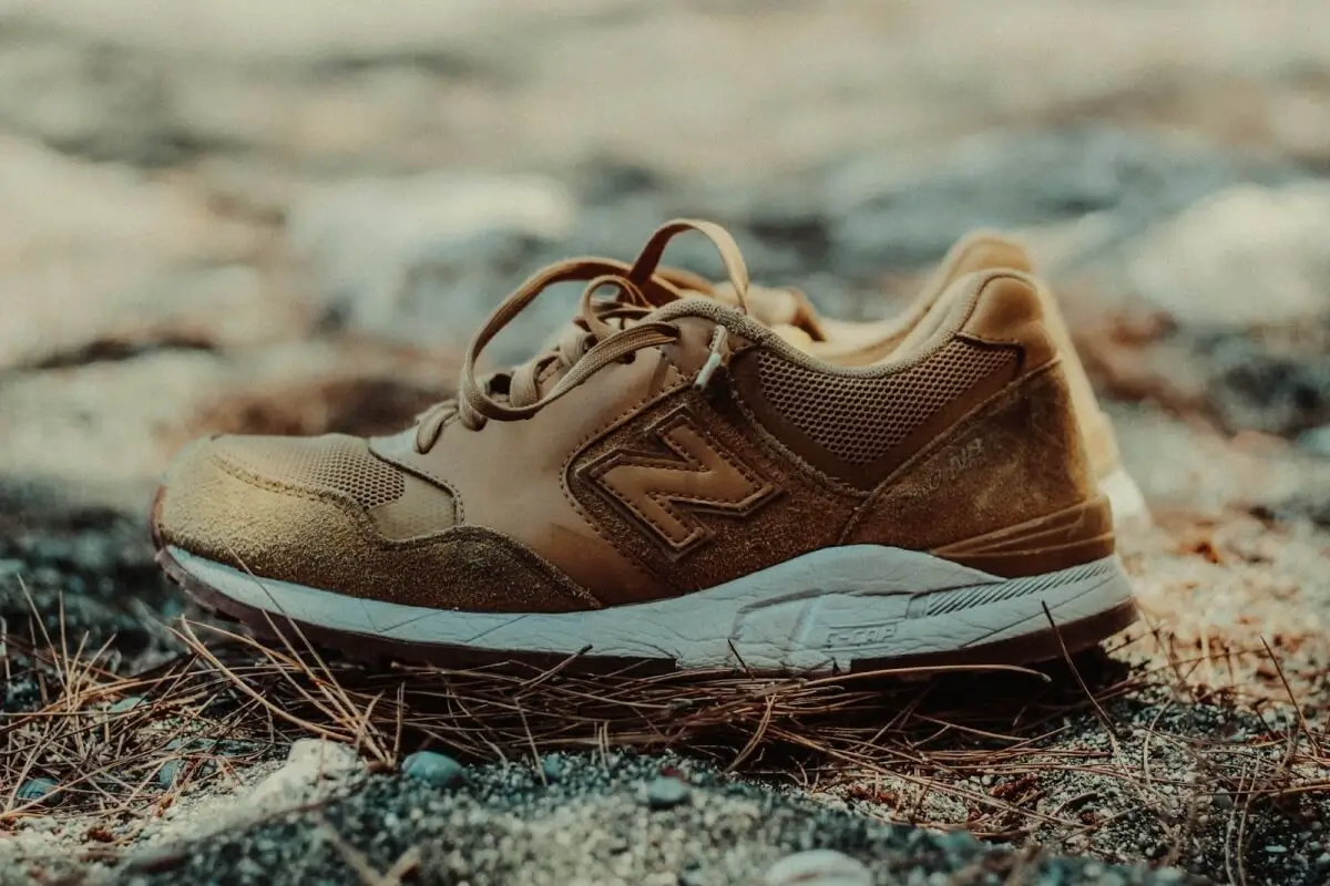 Image of a brown new balance walking shoe on the ground. The shoe is made of leather and other durable materials with a visible mesh upper and a rubber outsole.