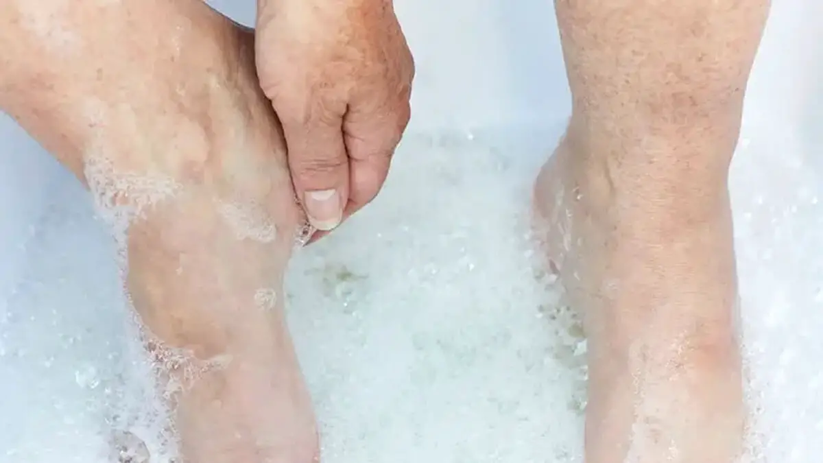 Senior woman washing her heels in soapy water.