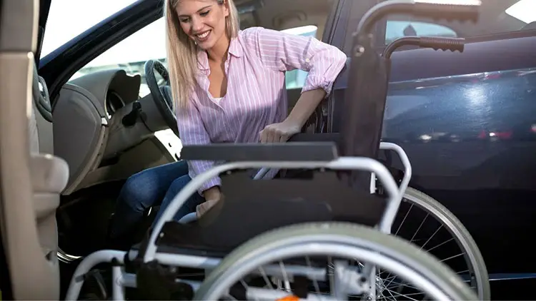 woman moving from car to wheelchair