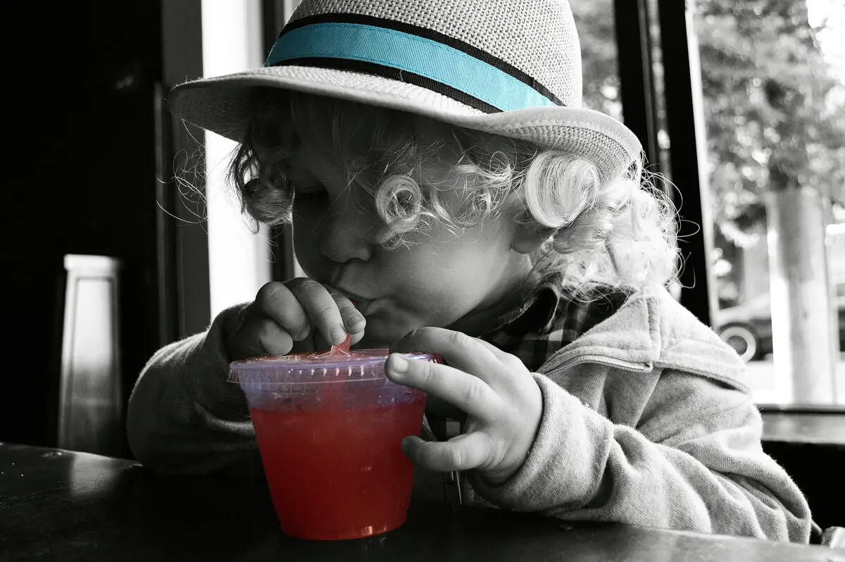 Pediasure for adults feature image of a young girl drinking a red colored liquid possibly containing nutritional supplements 