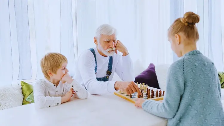 grandfather playing chess with grandchildren