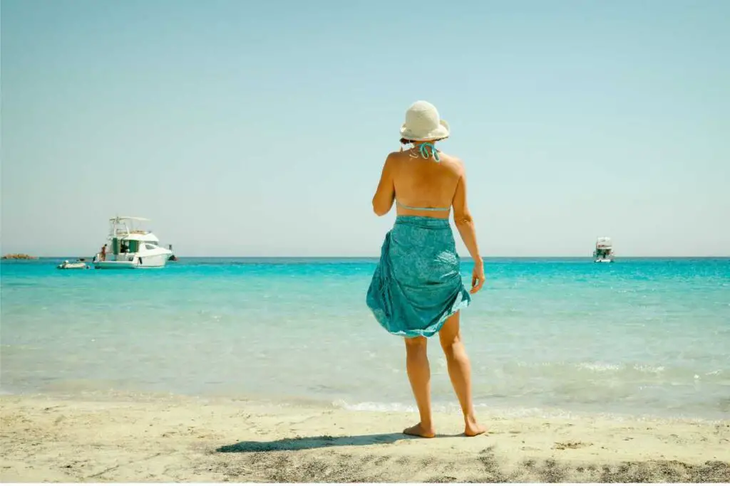 a woman looking out at the sea, seeming to enjoy her life in a bikini on vacation