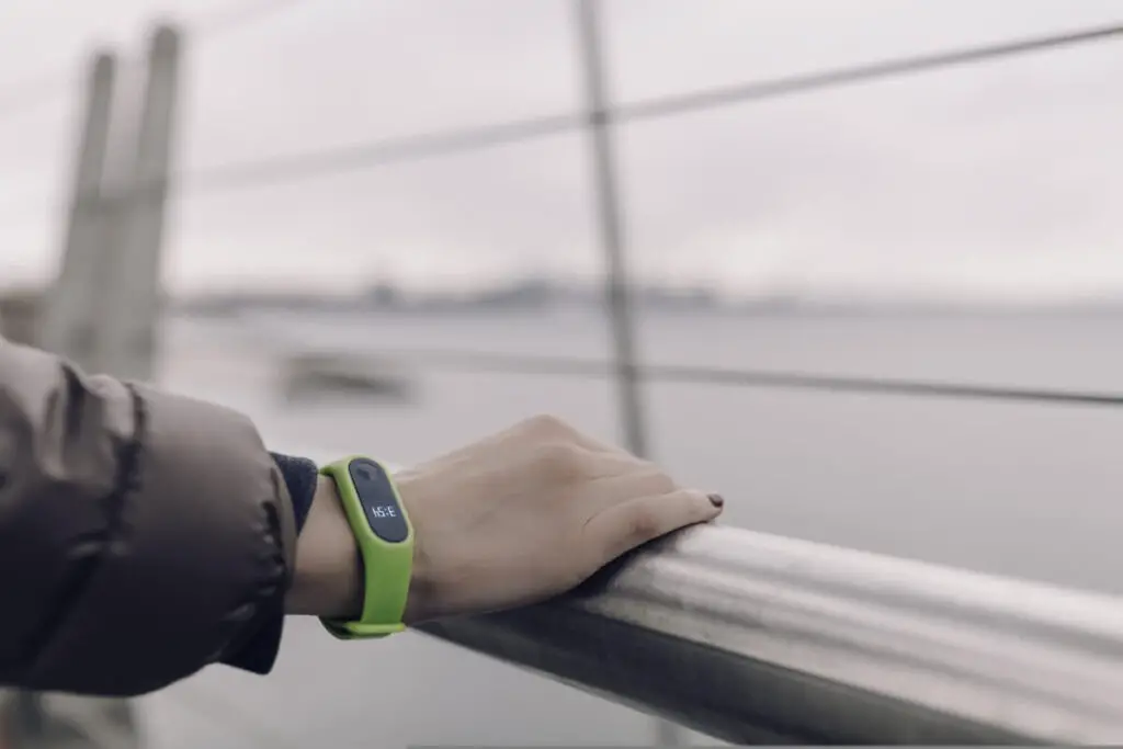 A person wearing a green fitness band that likely tracks exercise intensity along with other health metrics such as sleep score for good overall health