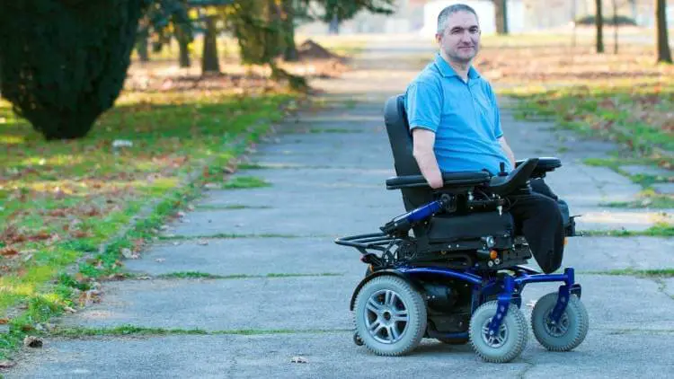Handicapped man in an electric wheelchair in a public park