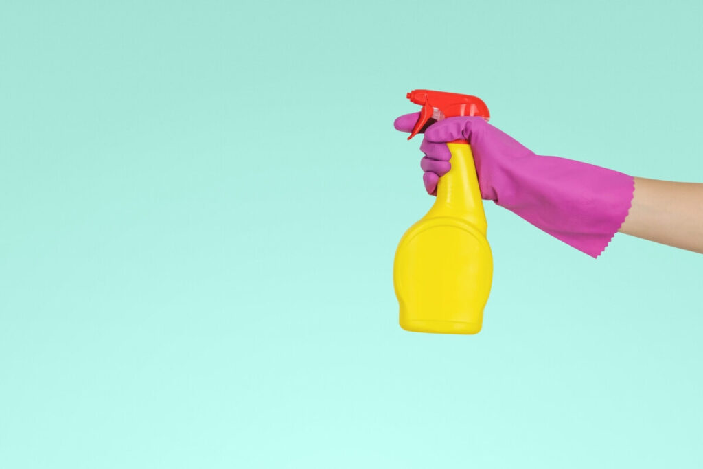 a gloved hand holding a spray bottle ready to do some efficient cleaning with a versatile cleaning solution