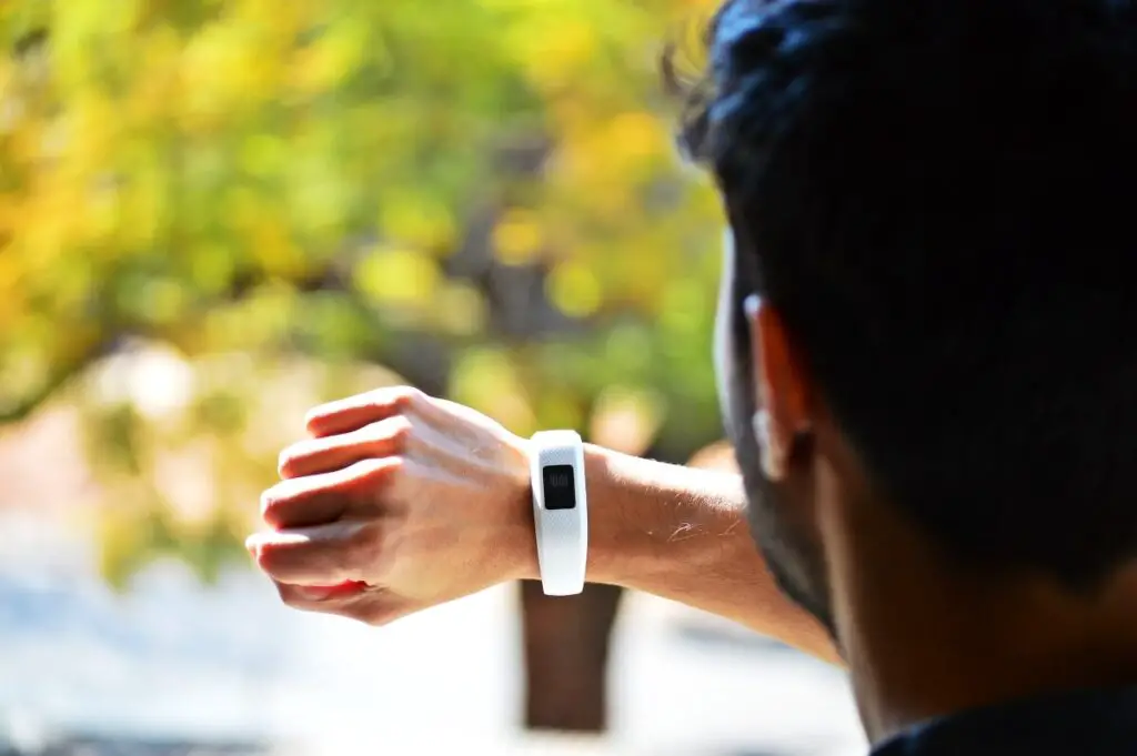 a man looking at a fitbit device on his wrist, which is one of the top fitness trackers to support a healthy lifestyle