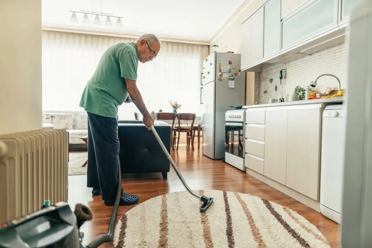 lightweight vacuum cleaners for seniors - elderly man vacuuming to maintain a clean and healthy environment