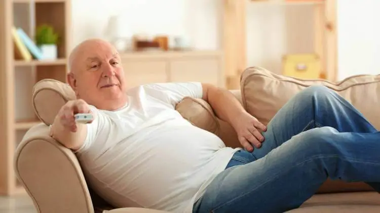 retired fat senior lying on sofa watching tv