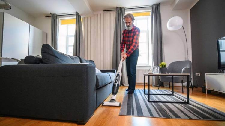 senior man cleaning home using vacuum cleaner