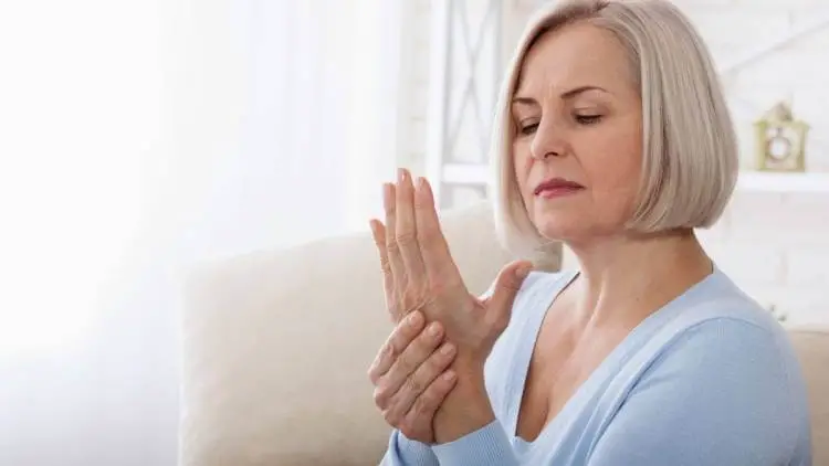 senior woman massaging her arthritic hands and wrist
