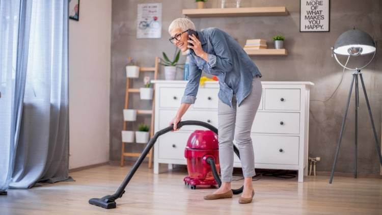 senior woman vacuuming house with ease while on phone