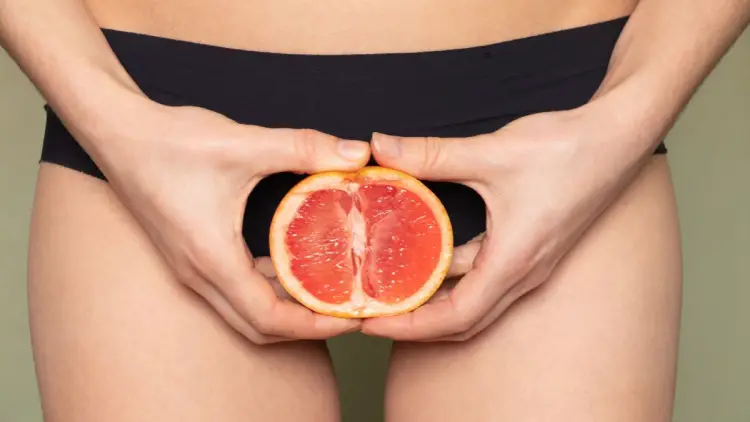 girl holding grapefruit in lower abdomen