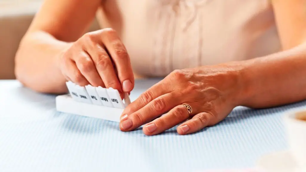 elderly woman placing pill into a pill box