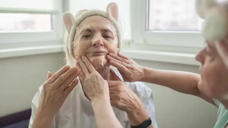 senior woman applying facial mask