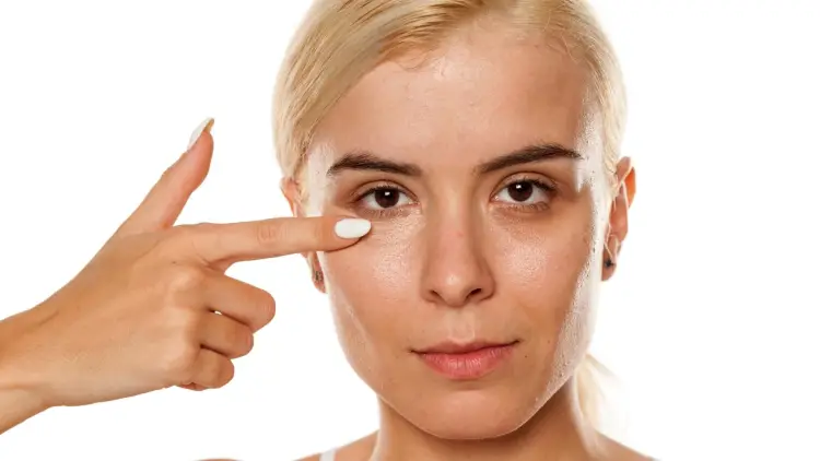 woman applying concealer under eyes