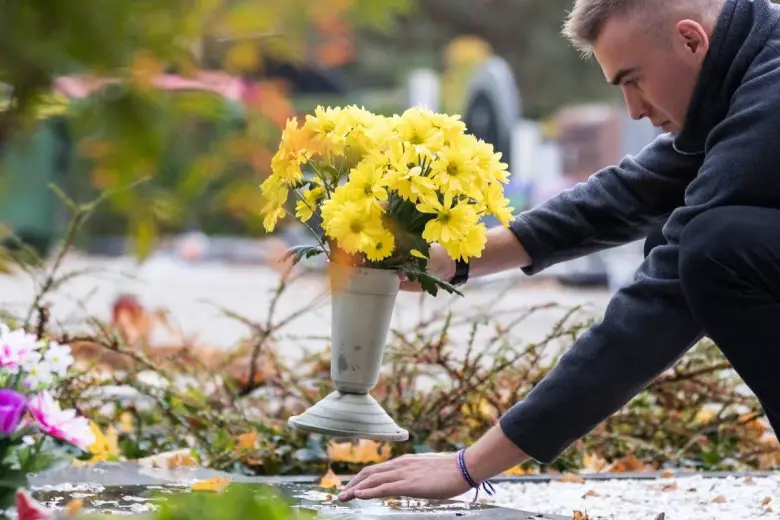 man putting her favorite flowers on grave trying to say happy anniversary in heaven