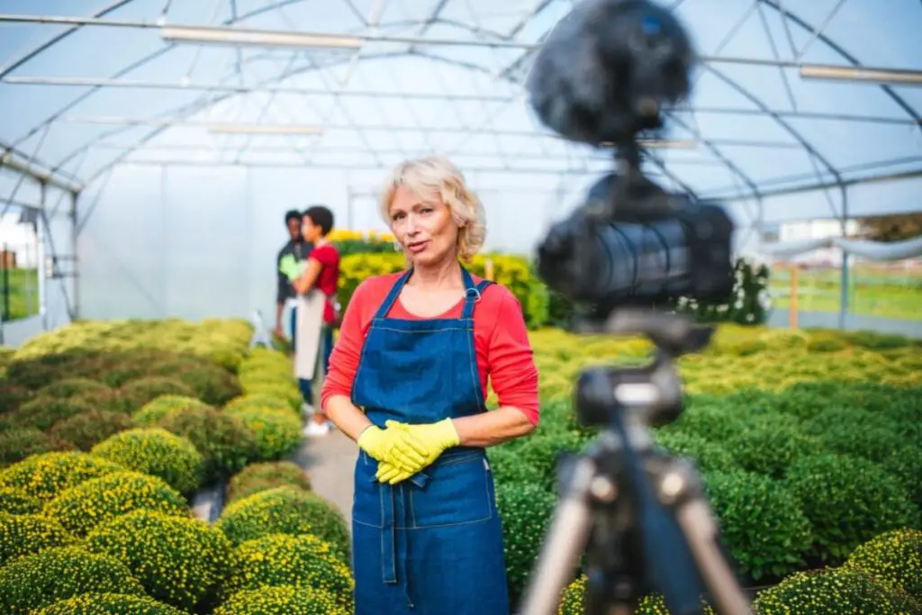 older woman making YouTube video in a greenhouse