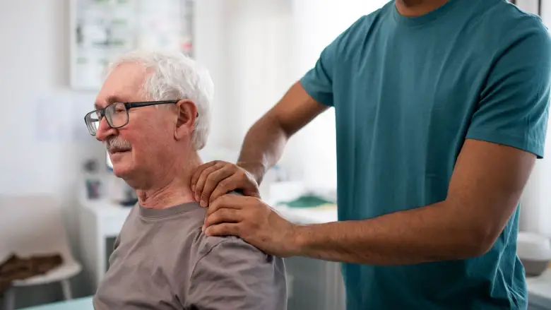 Physiotherapist conducting geriatric massage on the neck of elderly patient