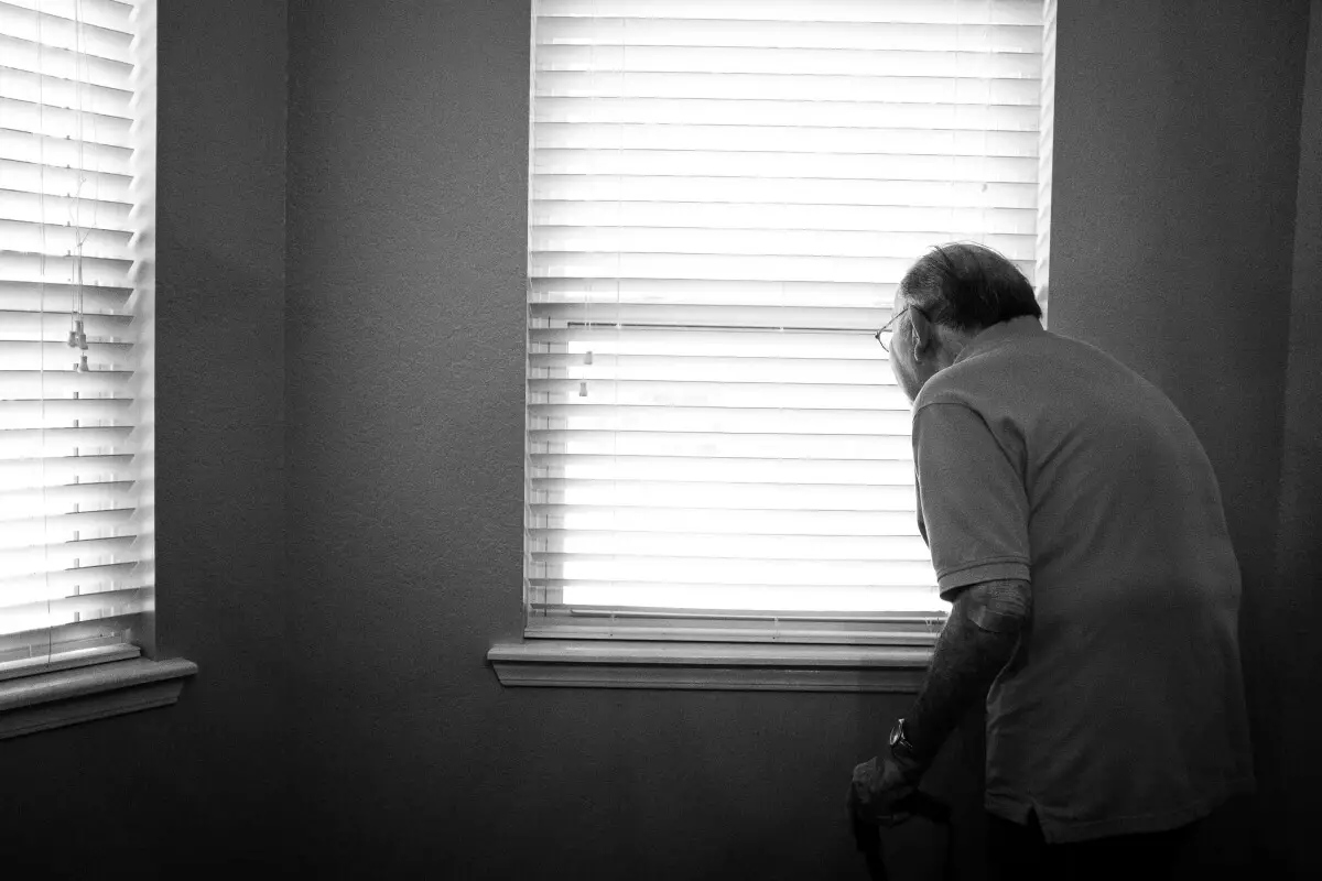 a senior man with a fall alert system in his home, helping to prevent emergency services needing to be called in case of a fall