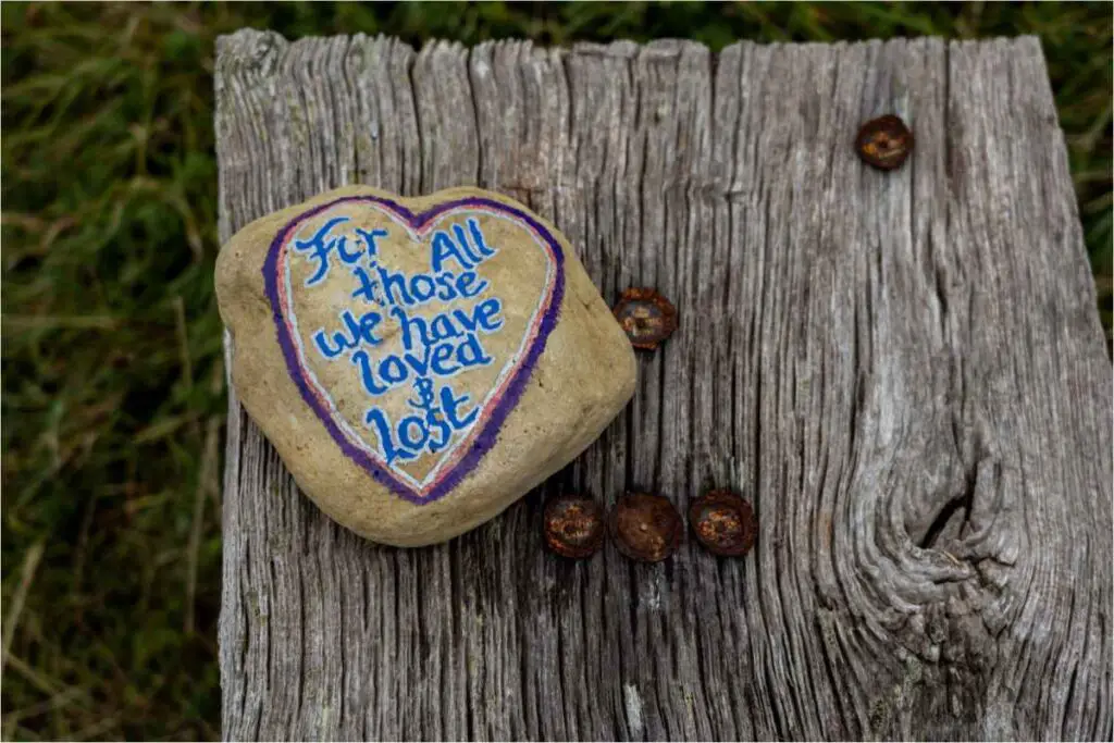 a painted rock with the words ' for all those we have loved and lost' - heartfelt words for those who are grieving