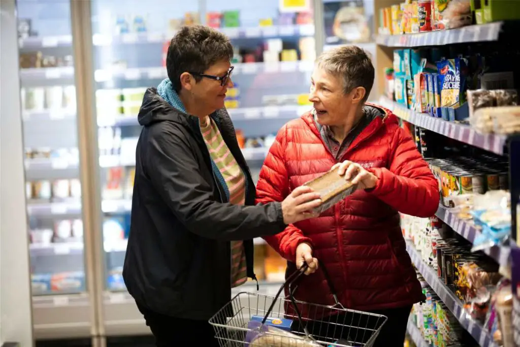 an adult child helping her aging parent with physical challenges grocery shop to ensure positive parents care as she ages