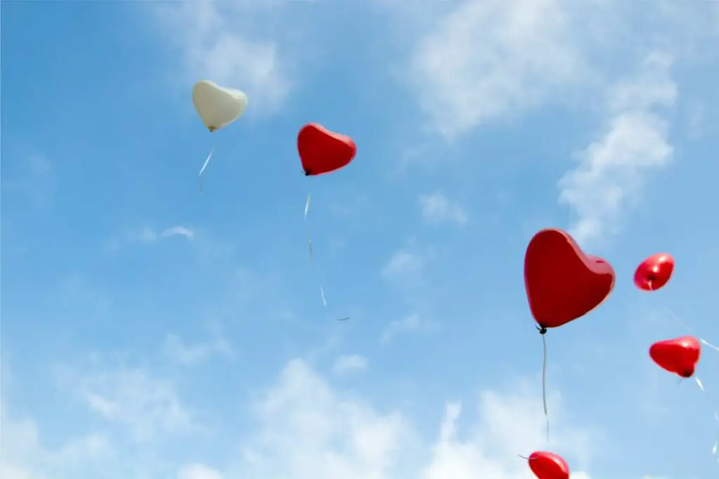 heart shaped balloons being sent up into the sky after a memorial service for a loved one during a difficult time