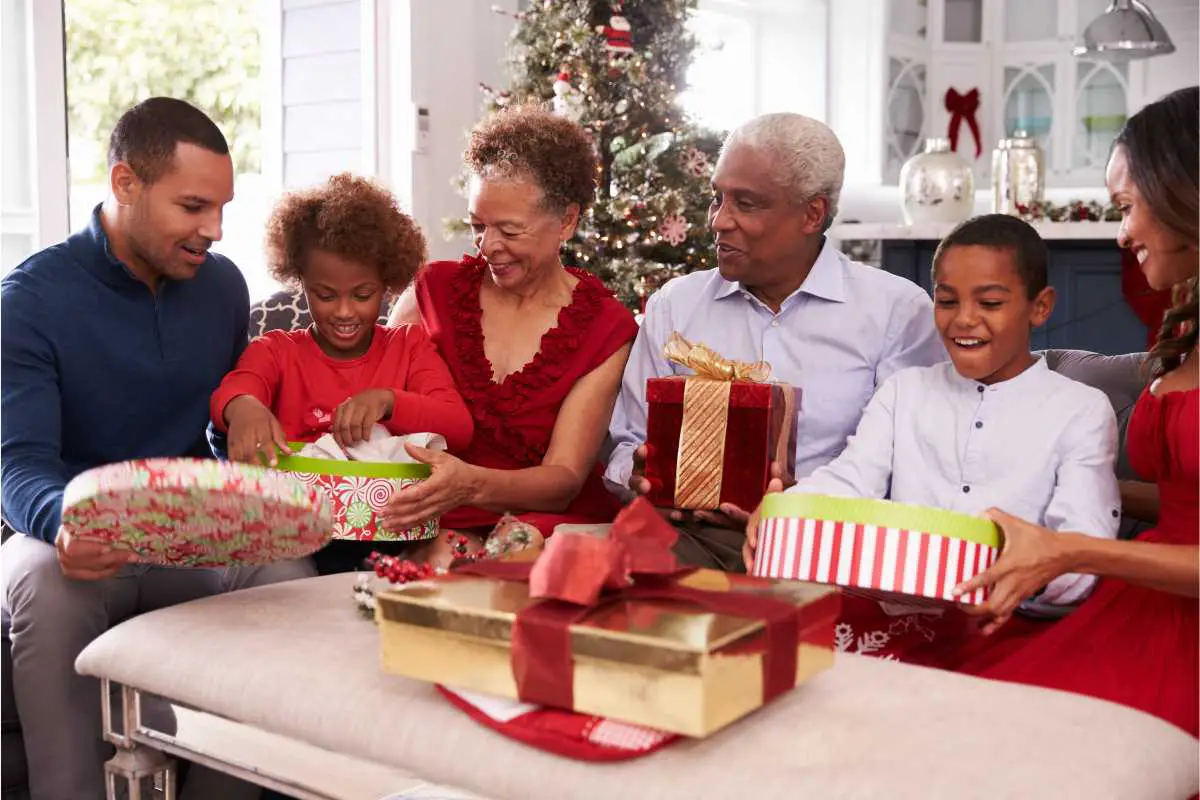 Older adults surrounded by family, opening exciting gifts such as fun puzzles, gardening tools, and gifts for the golf pro! 