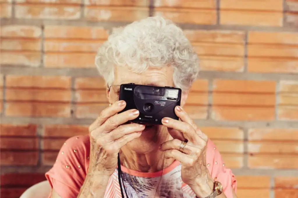 an older woman taking an old school photograph with a camera held up to eye level, blocking her face
