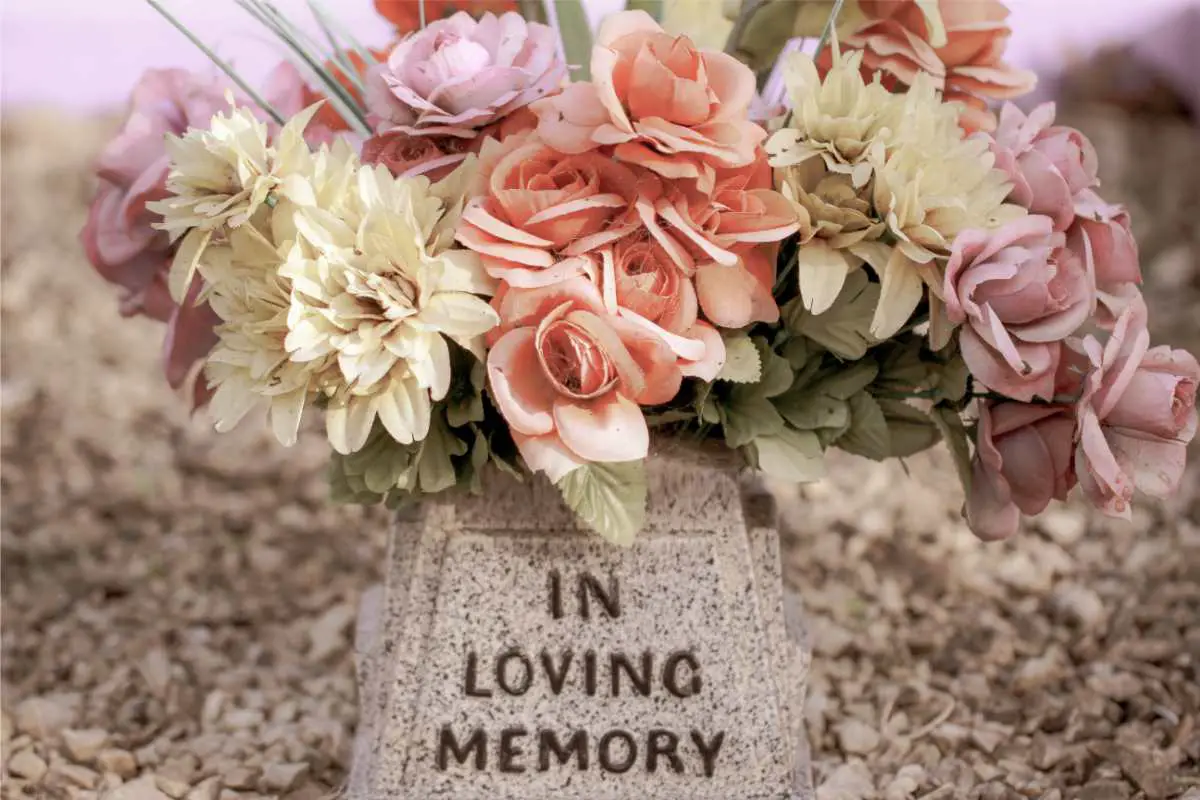 in loving memory plaque with flowers above it to honor someone gone too soon - may they rest in peace
