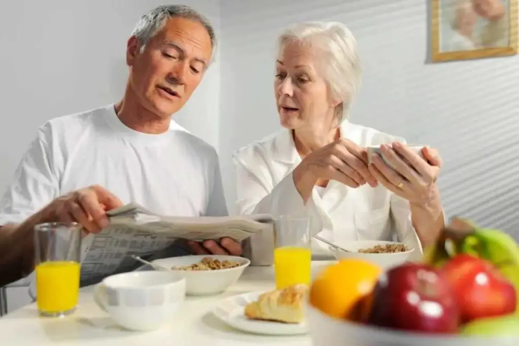 two older adults discussing their weight gain goals over a high calorie breakfast such as breakfast buckwheat bowls, scrambled eggs, and orange juice