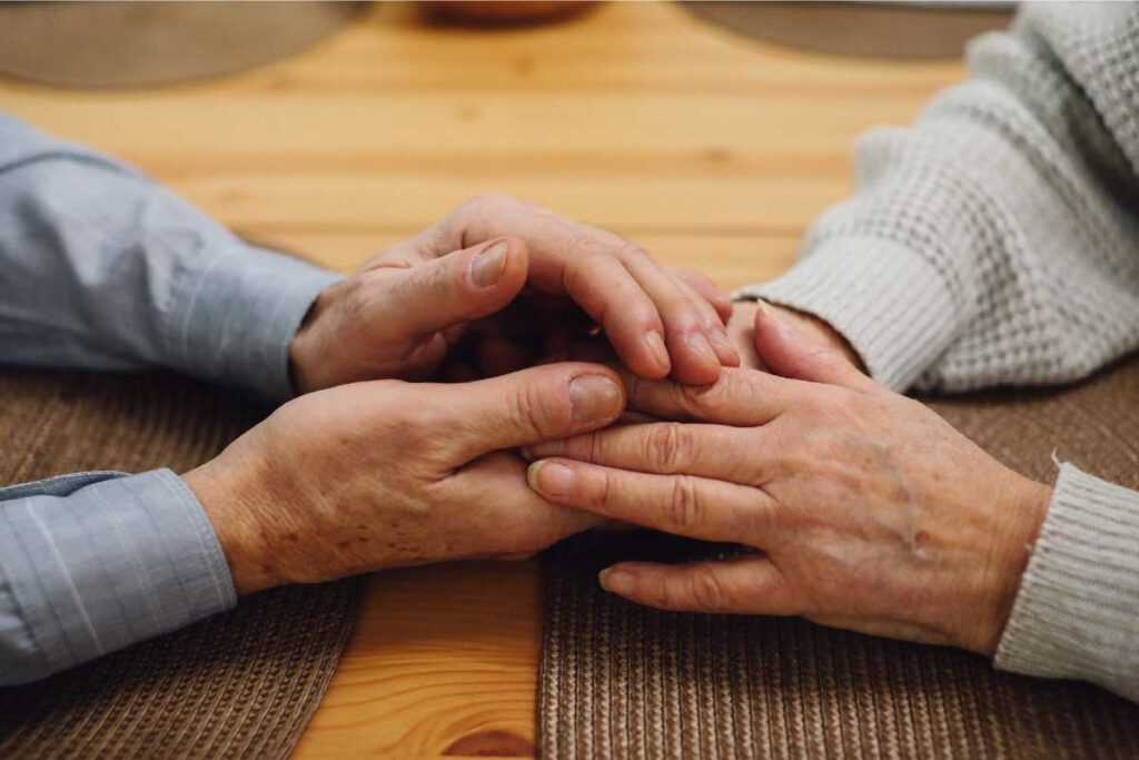 two people holding hands across a table, both with clean, cut nails showing signs of overall health 