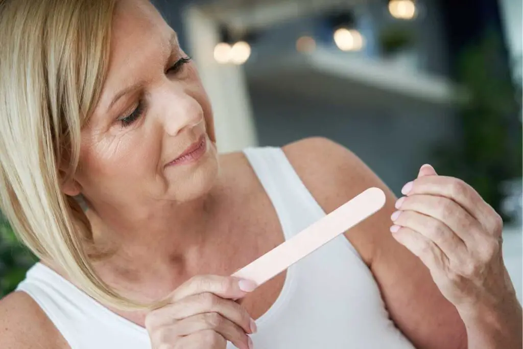 a woman with thinner nails using a file or emery board instead of fingernail clippers